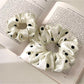 Gifty satin scrunchie with white polka dots displayed on a white surface