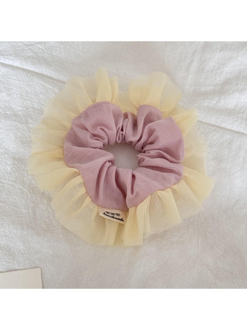 Close-up of Gifty tulle scrunchie showing layered ruffle texture in pink and beige