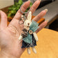 Rabbit charm keychain hanging from a decorative hook on a wall