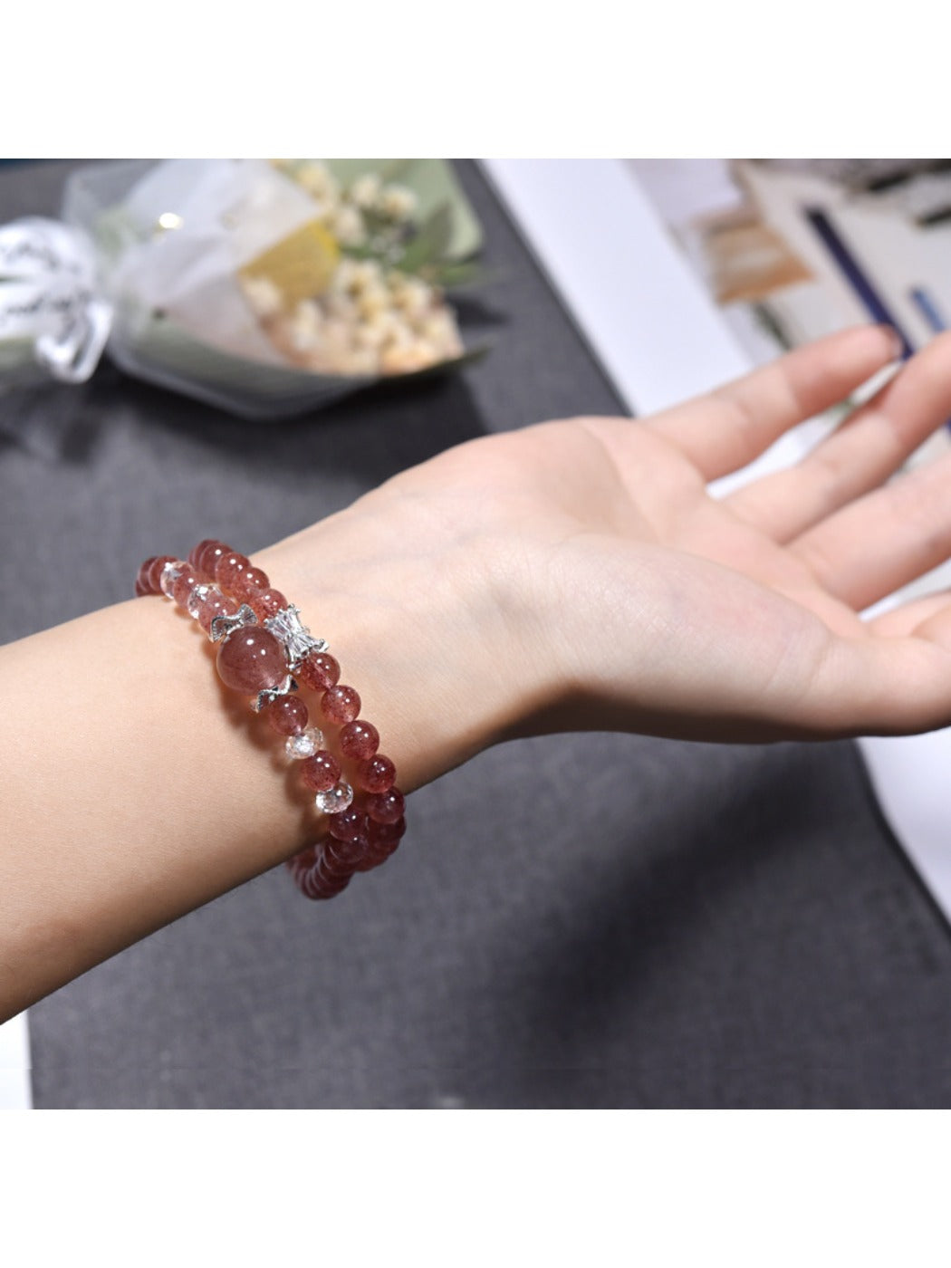 Lovra bracelet wrapped multiple times around wrist showcasing pink strawberry quartz stones