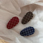 Side angle of oval polka dot hair clip highlighting smooth edges