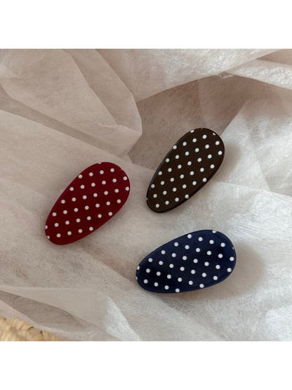 Side angle of oval polka dot hair clip highlighting smooth edges