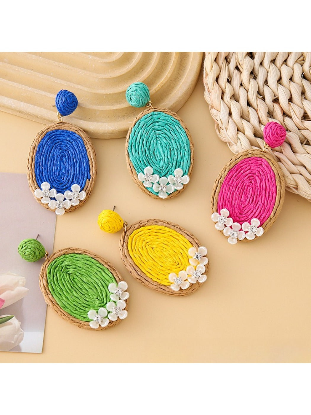 Close-up of Earedge raffia woven oval shape earrings on white background
