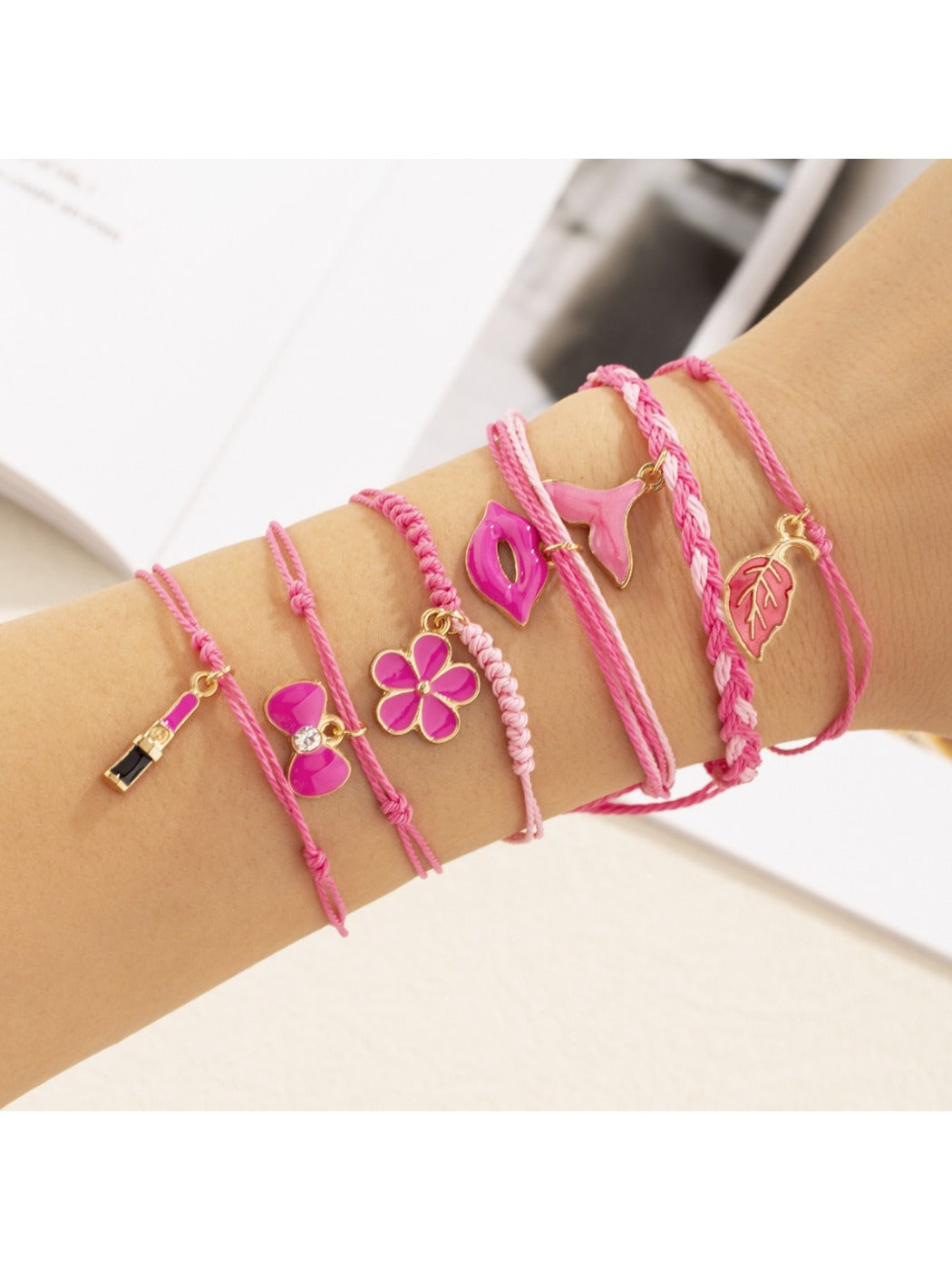 Lovra woven bracelet displayed on wrist featuring lipstick bow pendant