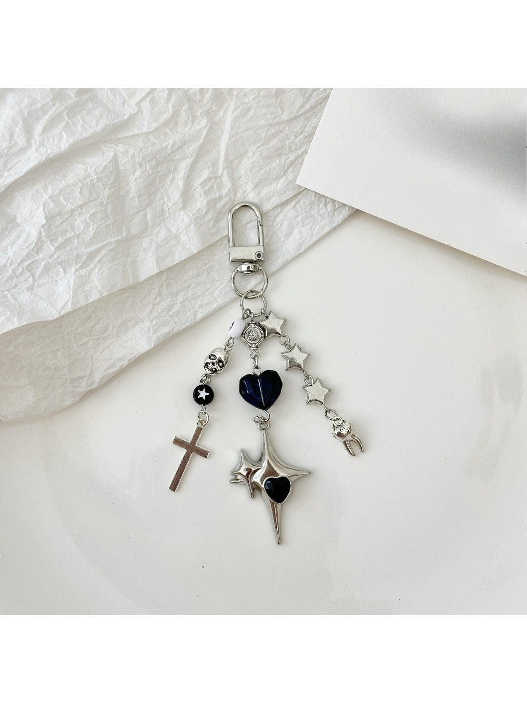 Silver cross keychain hanging from a set of keys on a wooden surface