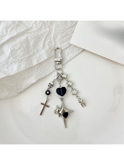 Silver cross keychain hanging from a set of keys on a wooden surface