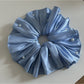 Large satin scrunchie in beige color with a subtle sheen under soft lighting