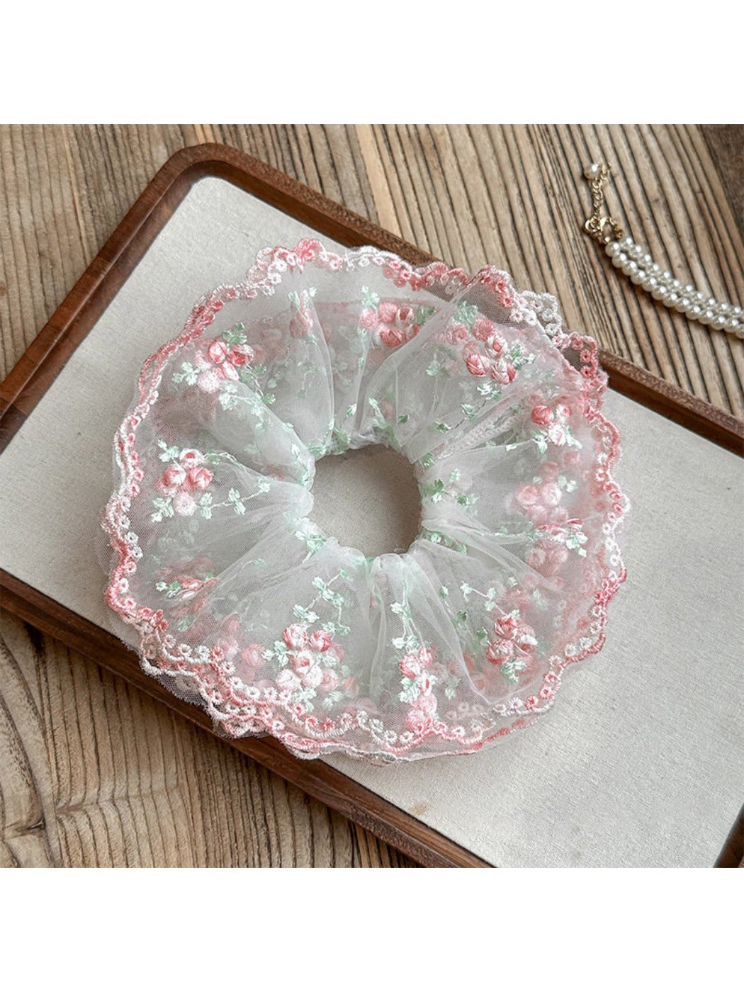 Pink ruffled scrunchie styled with casual outfit on a wrist