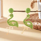 Detailed shot of the flamingo pendant earring showing pink enamel and metal details