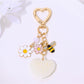 Heart shaped keychain covered in rhinestones with metal keyring on neutral background