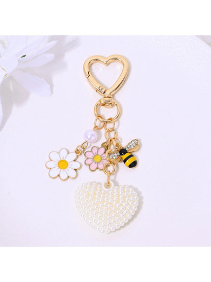 Heart shaped keychain covered in rhinestones with metal keyring on neutral background