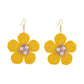 Top view of raffia flower earrings emphasizing the circular woven pattern and gold backing