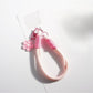 Keypus keychain with vibrant flower design hanging from a bag zipper