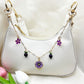 Close-up of delicate daisy pendant bag charm with gold chain on white background