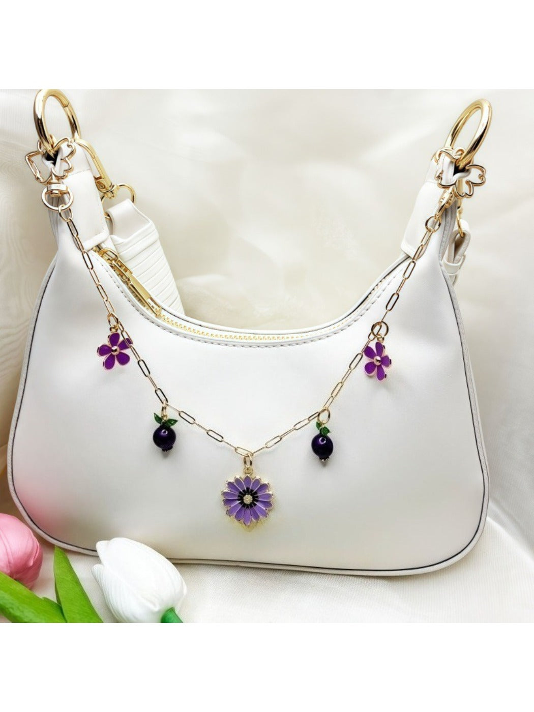 Close-up of delicate daisy pendant bag charm with gold chain on white background