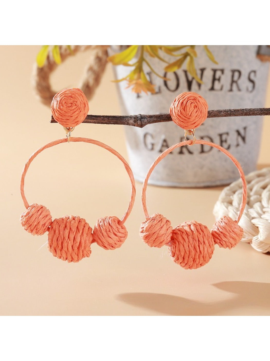 Earedge raffia round ball earrings worn on a model's ear