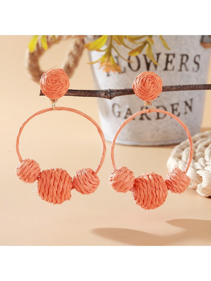 Earedge raffia round ball earrings worn on a model's ear