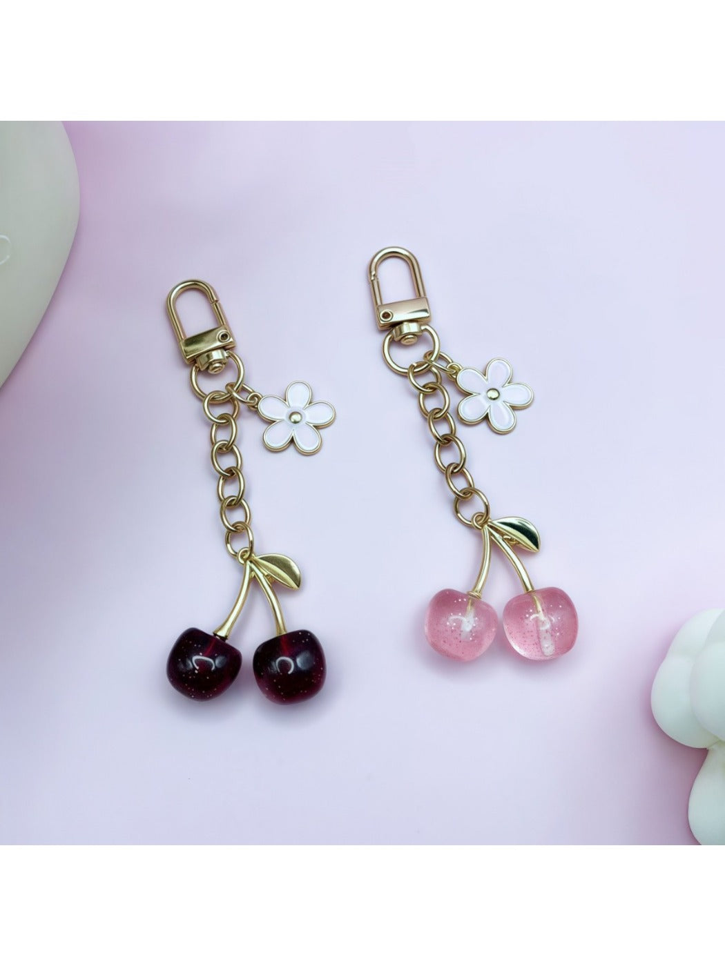 Close-up of a stylish cherry charm keychain with red enamel cherries and green leaves