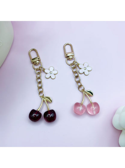 Close-up of a stylish cherry charm keychain with red enamel cherries and green leaves