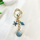 Keypus pendant keychain resting on a blue fabric, emphasizing its color contrast