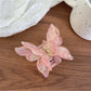 Pastel pink butterfly claw clip placed on a wooden surface