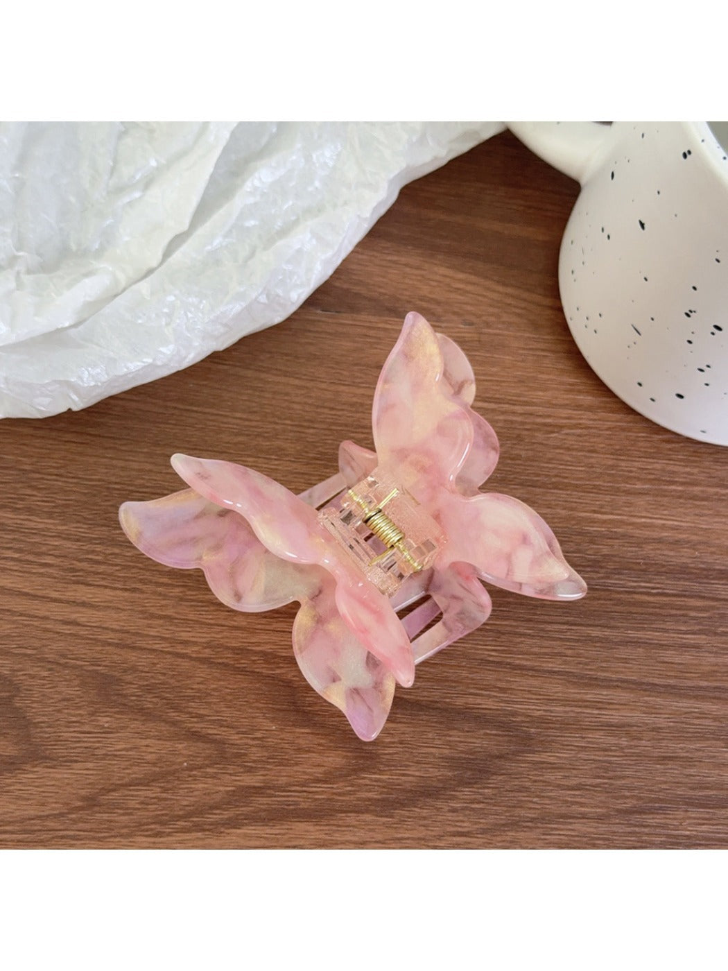 Pastel pink butterfly claw clip placed on a wooden surface