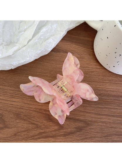 Pastel pink butterfly claw clip placed on a wooden surface
