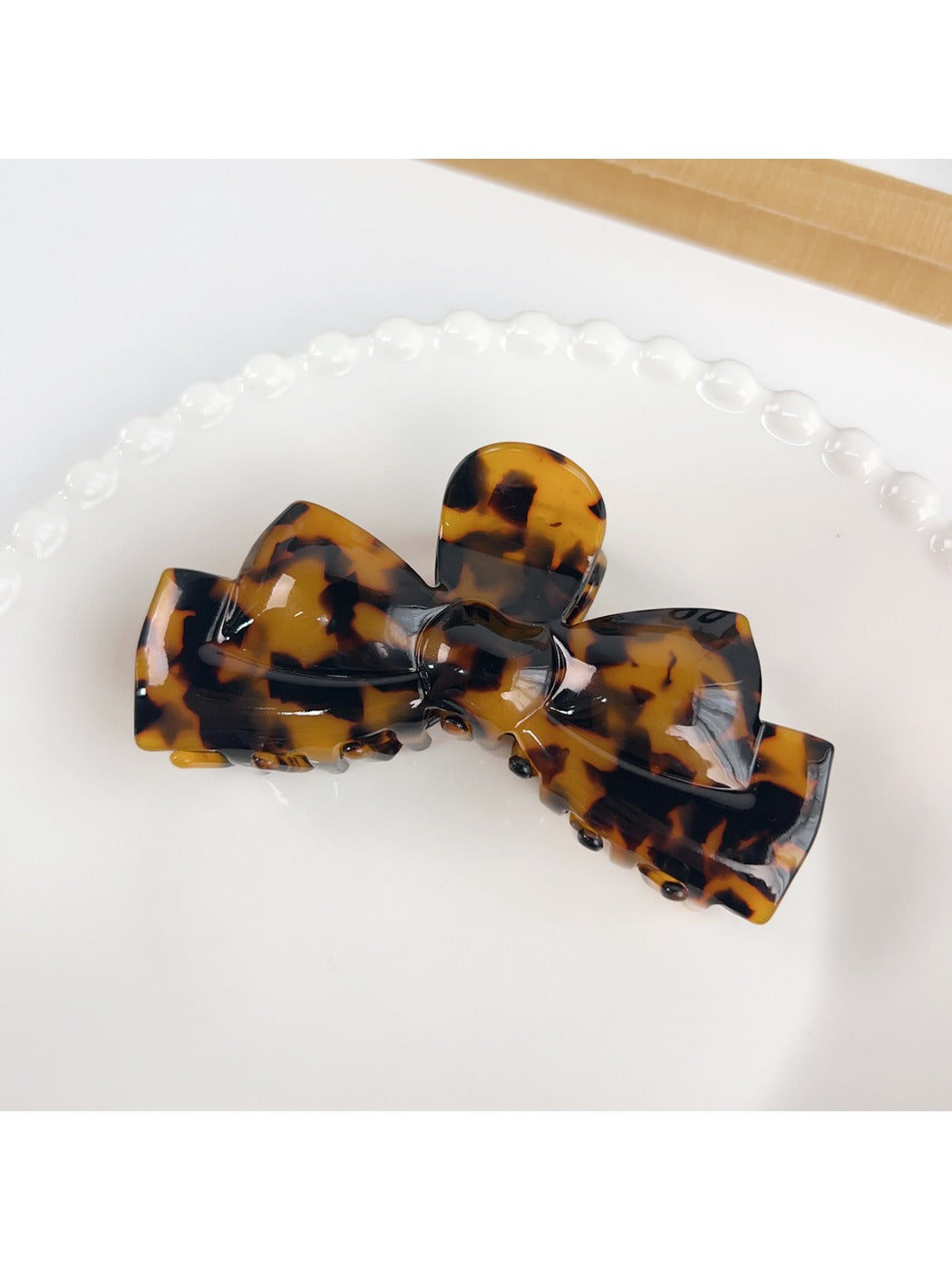 Beau bow shaped hair claw clip in beige held in hand