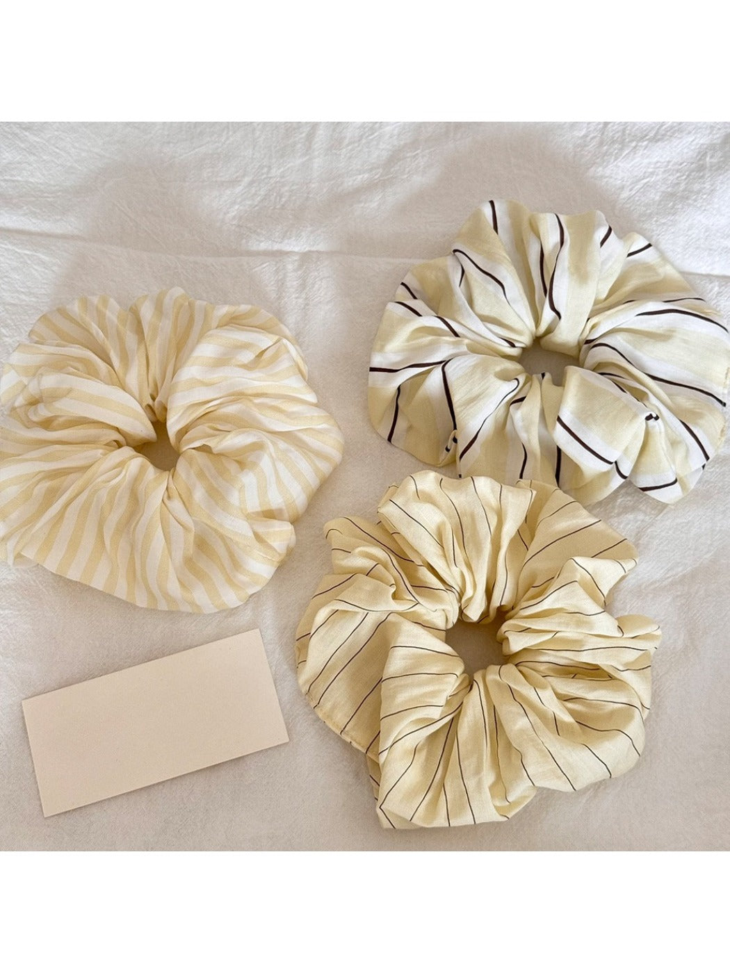 Yellow scrunchie with white and orange stripe print on a white background