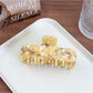 Beau square hair claw clip placed next to matching minimalist accessories