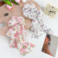 Gifty scrunchie displayed on a white background showing ruffled floral pattern and bow detail