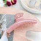 Pastel curved claw clip in lavender and cream colors on neutral backdrop