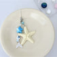 Keychain placed on a white surface highlighting starfish and fish charms