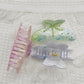 Beau rainbow claw clip shown open, displaying curved teeth for secure hold