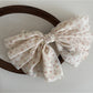 Beau chiffon bow hair clip in soft pink held in hand showing size and detail