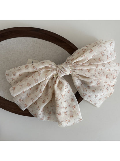 Beau chiffon bow hair clip in soft pink held in hand showing size and detail