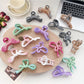 Beau ombre heart shaped bow claw clip in pink and purple gradient on white background
