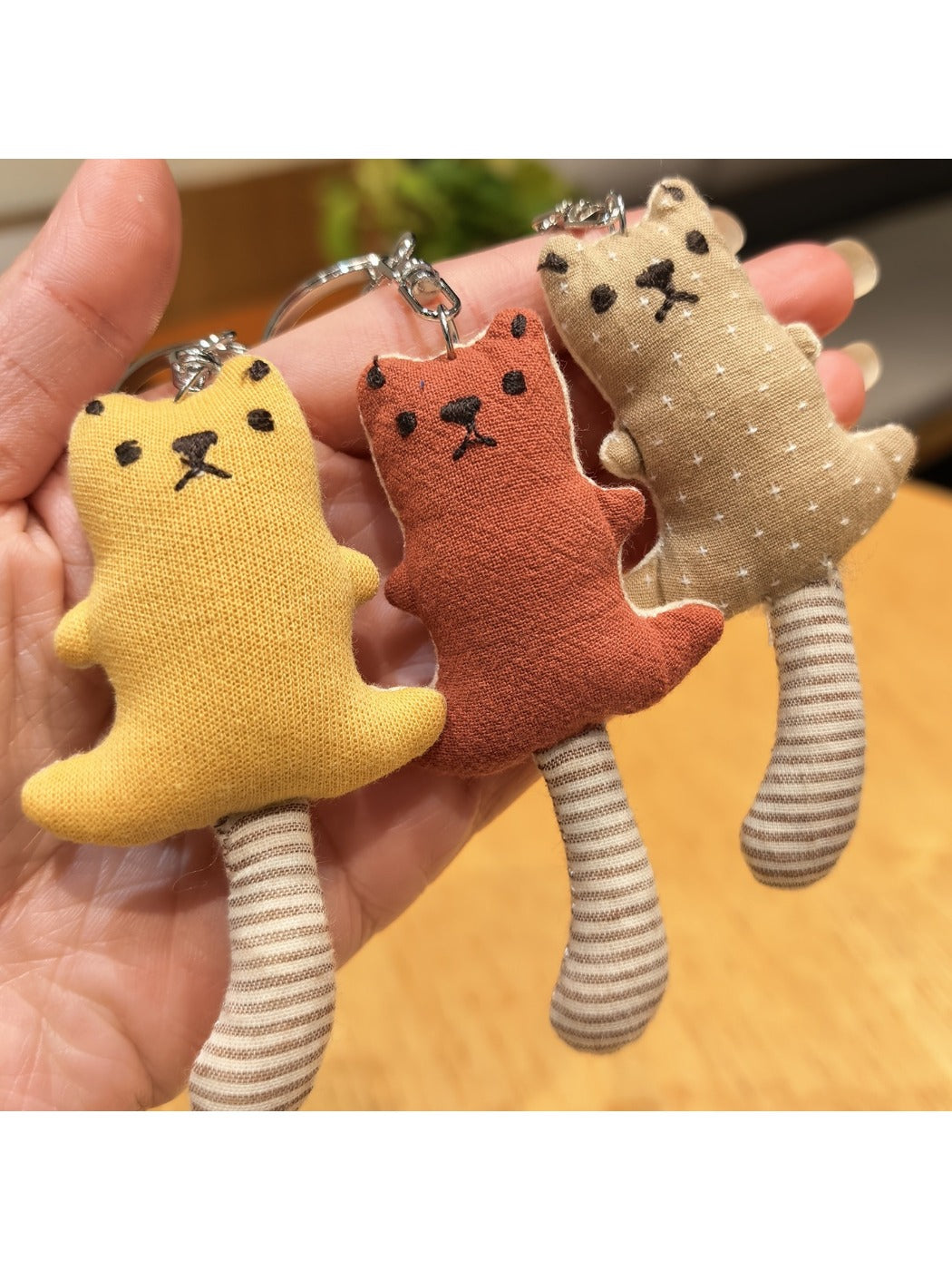 Side view of the long-tailed bear keychain highlighting its tail and plush texture