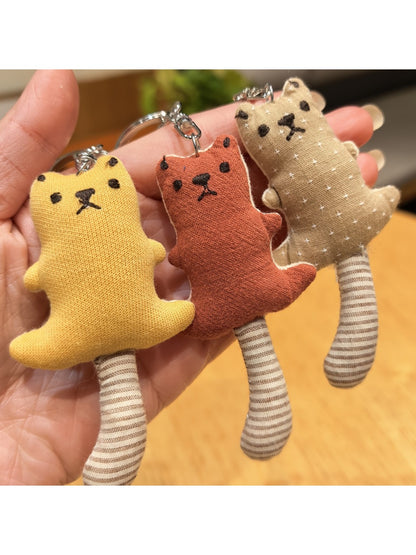 Side view of the long-tailed bear keychain highlighting its tail and plush texture