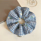 Blue plaid scrunchie with embroidered white flower detail on fabric