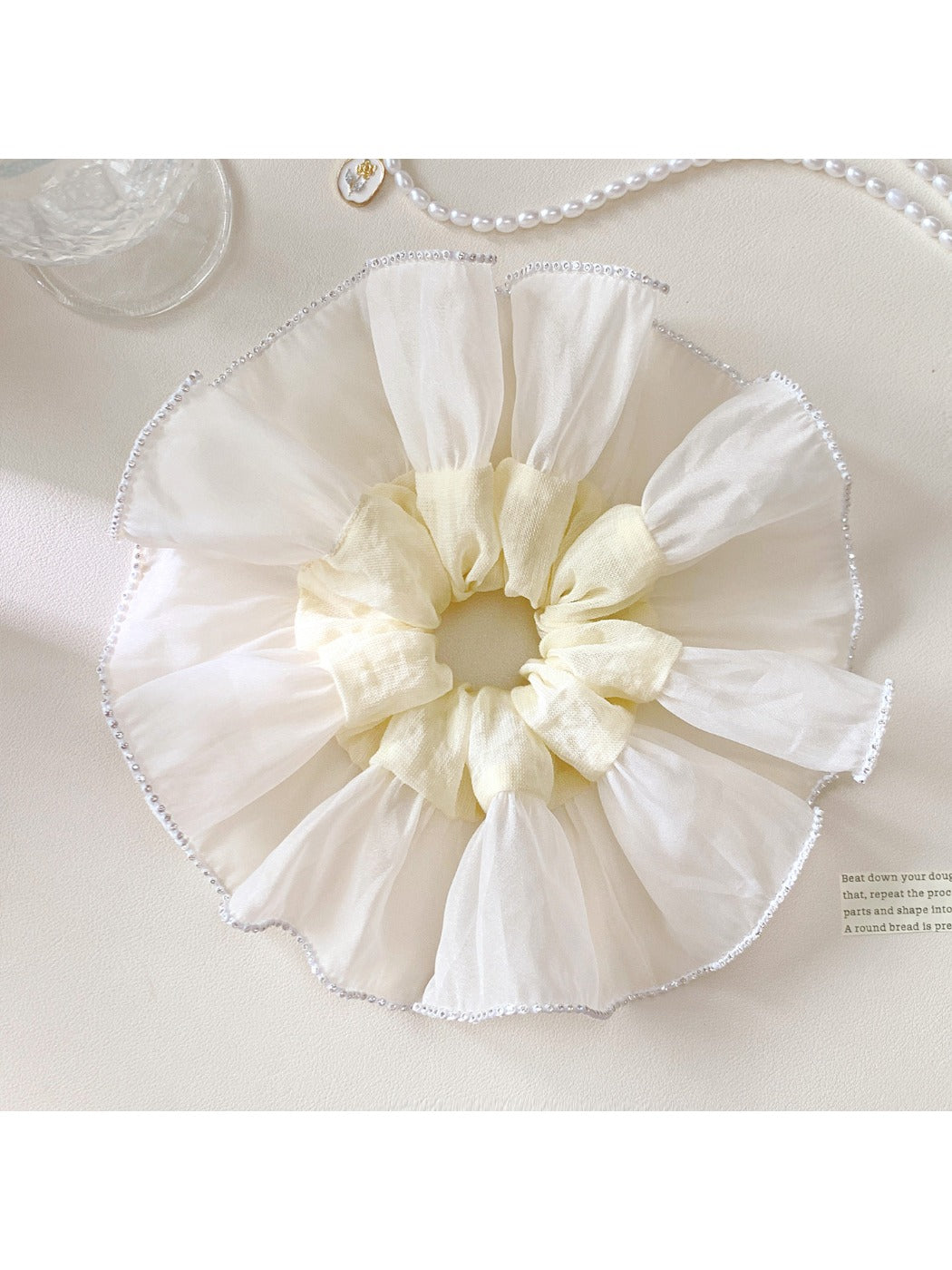 Elegant white silky scrunchie with smooth texture on a plain background
