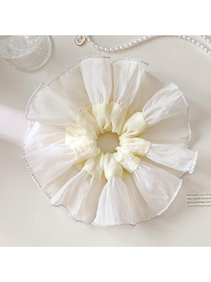 Elegant white silky scrunchie with smooth texture on a plain background