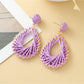 Earedge woven drop earrings hanging from a branch with natural light