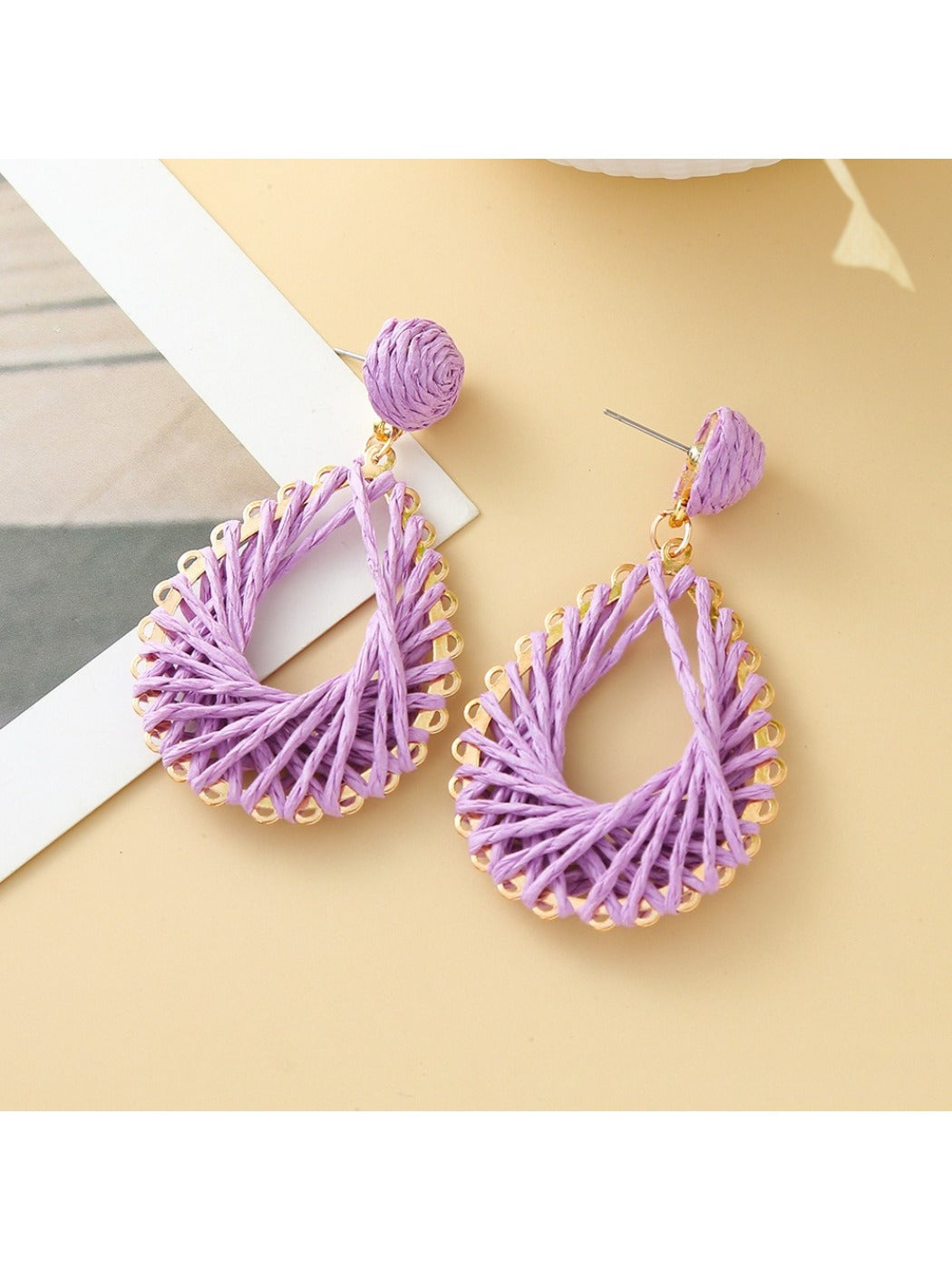 Earedge woven drop earrings hanging from a branch with natural light
