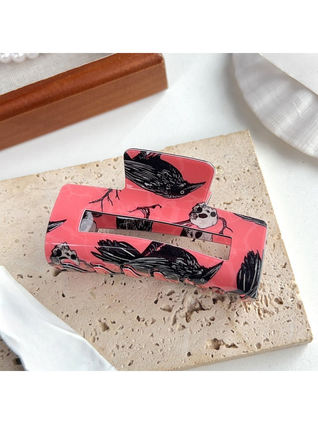 Beau hair claw clip placed on white surface showing full crow design