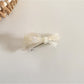 Beau hair clip in soft pink on a wooden surface with natural light