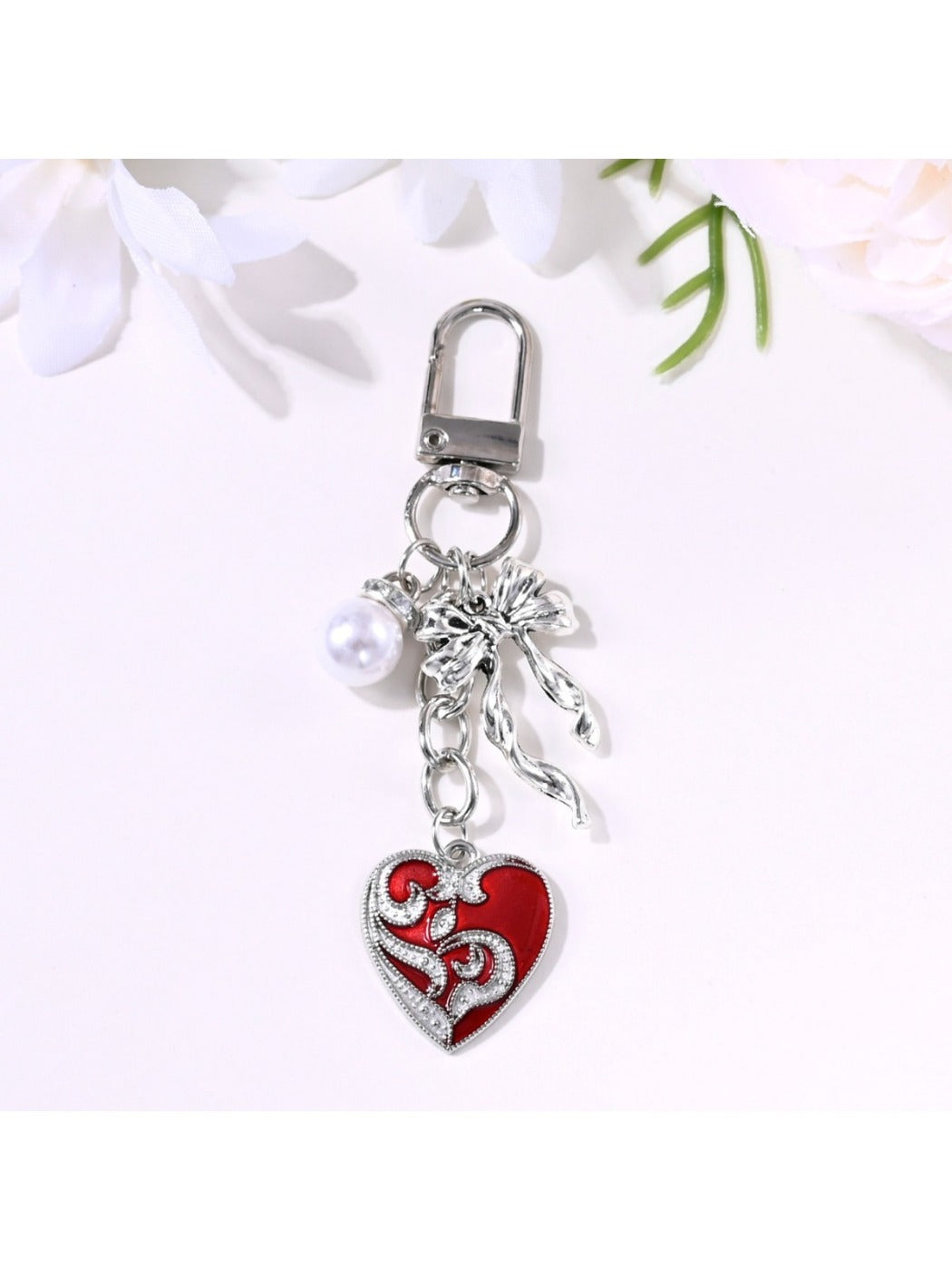 Alloy heart bow keychain photographed with a blurred floral background