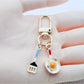 Keypus fried egg and spatula shaped keychain on white background