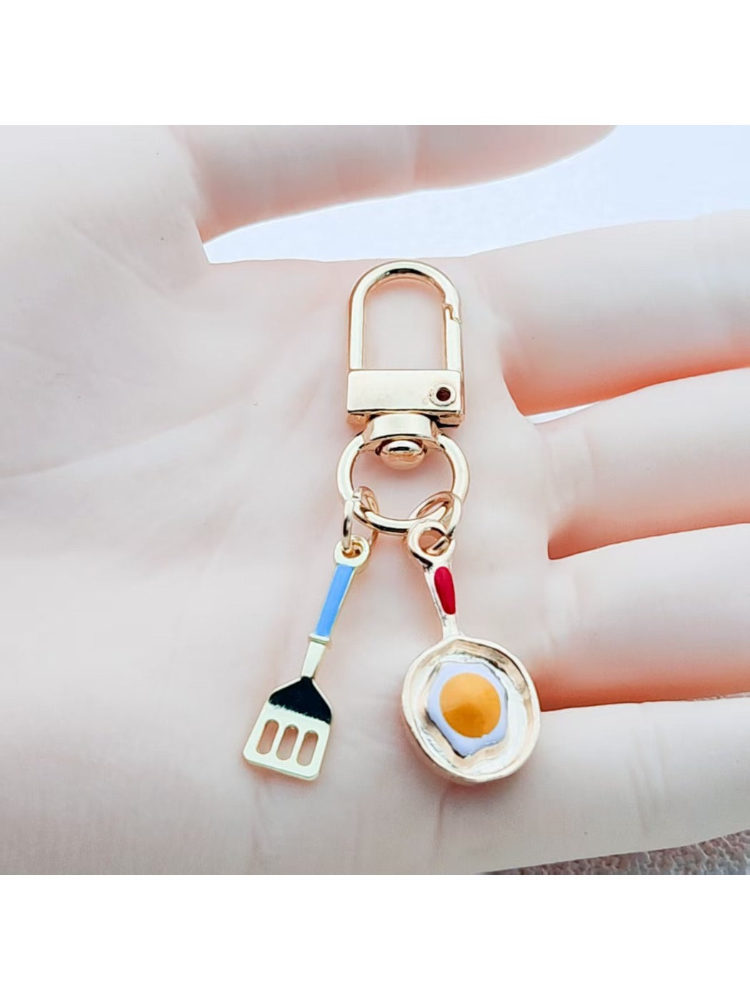 Keypus fried egg and spatula shaped keychain on white background