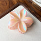 Beau flower shaped claw clip held between fingers showing grip